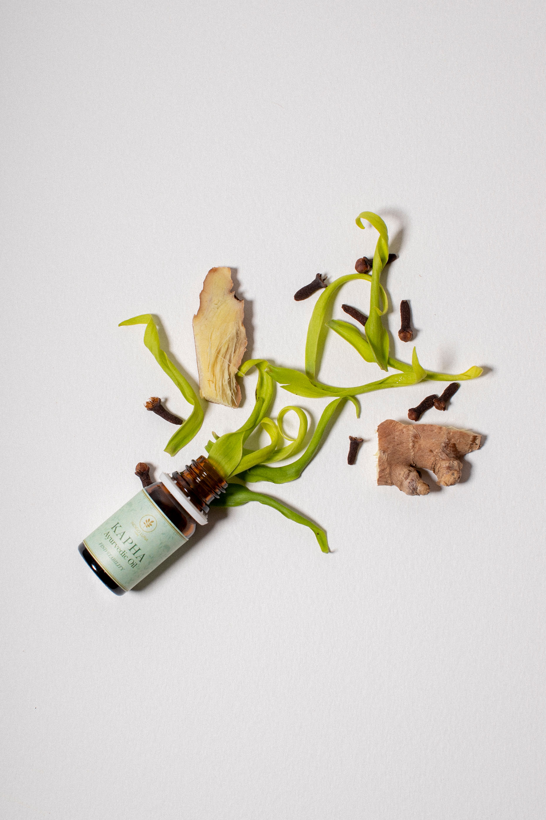 Ayurvedic essential oil for Kapha Dosha, image showing natural herbs coming out of the bottle